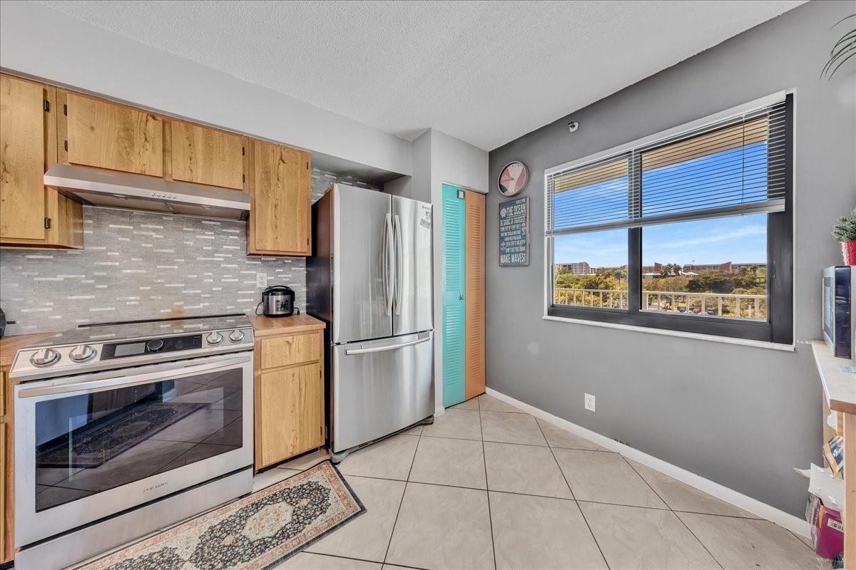 A kitchen with wood cabinets, stainless steel appliances, a tiled backsplash, and a large window — 2217 Cypress Island Drive # 507, Pompano Beach FL 33069, POMPANO BEACH, FL