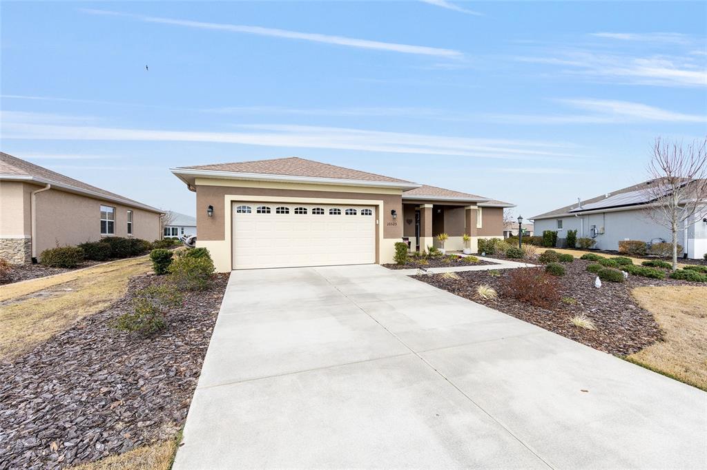 A single-story house with a beige stucco exterior, a two-car garage, and a concrete driveway — 10525 SW 90TH STREET ROAD, OCALA, FL