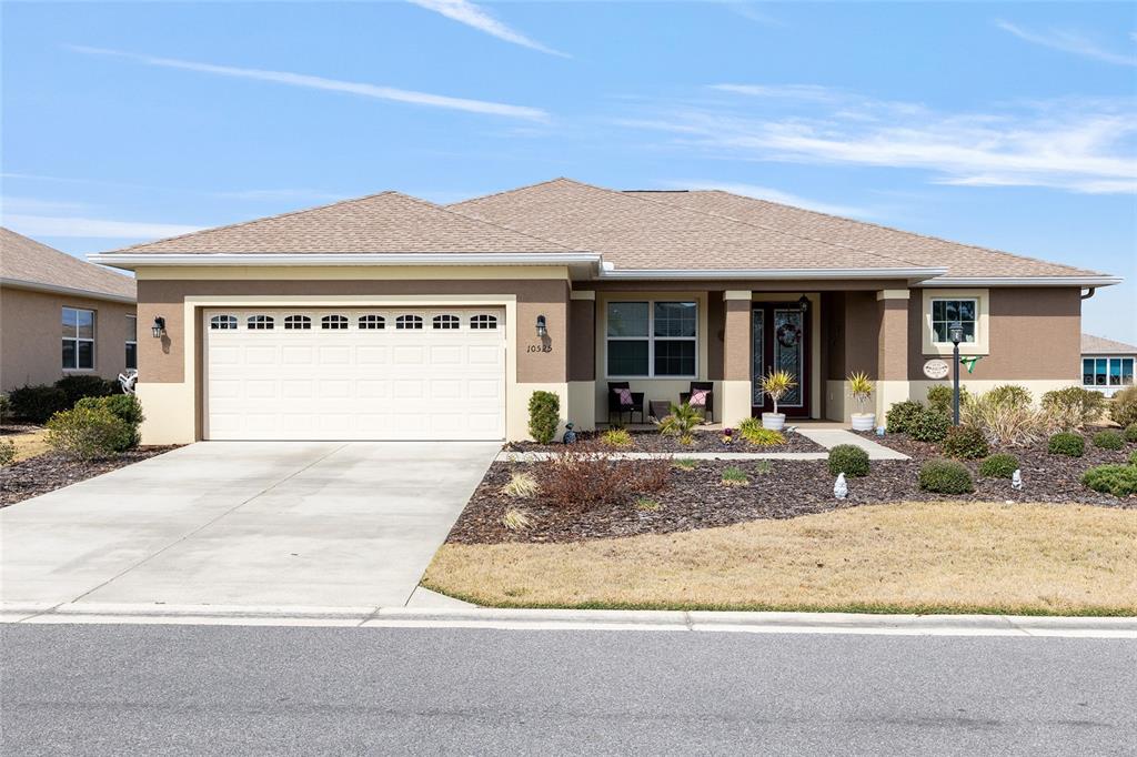 A single-story house with a two-car garage, tan stucco exterior, and a covered front porch — 10525 SW 90TH STREET ROAD, OCALA, FL