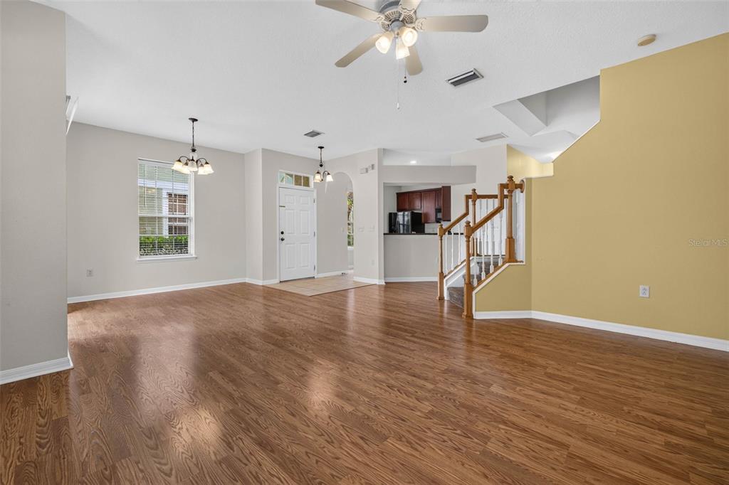 An open-concept living and dining area features hardwood floors, a staircase, and a ceiling fan — 27747 PLEASURE RIDE LOOP, WESLEY CHAPEL, FL