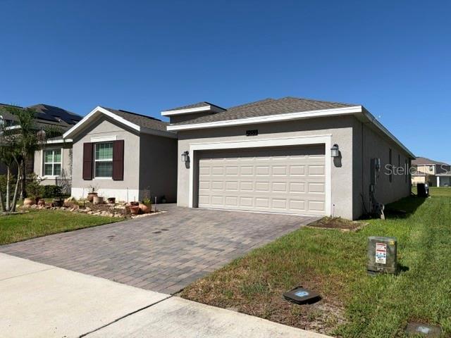 A single-story house with a beige stucco exterior, a two-car garage, and a paver driveway — 2959 CAMDEN WAY, DAVENPORT, FL