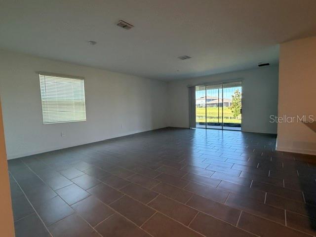 A spacious room features large gray floor tiles, white walls, and sliding glass patio doors — 2959 CAMDEN WAY, DAVENPORT, FL