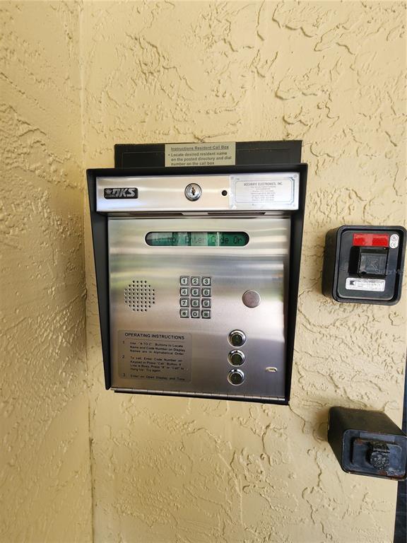 A wall-mounted metal intercom system with a keypad and buttons is attached to a textured wall — 13612 S VILLAGE DRIVE UNIT 5307, TAMPA, FL
