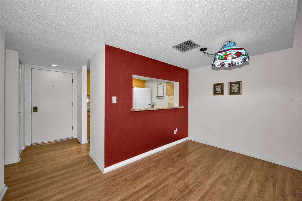 A dining area features wood-look flooring, a red accent wall, and a stained-glass pendant light — 13612 S VILLAGE DRIVE UNIT 5307, TAMPA, FL