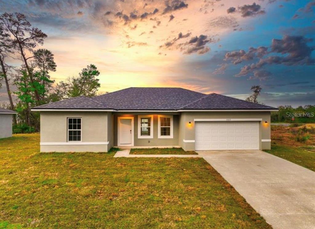 A single-story house with a light-colored stucco exterior, a two-car garage, and a shingled roof — 267 MARION OAKS GOLF ROAD, OCALA, FL