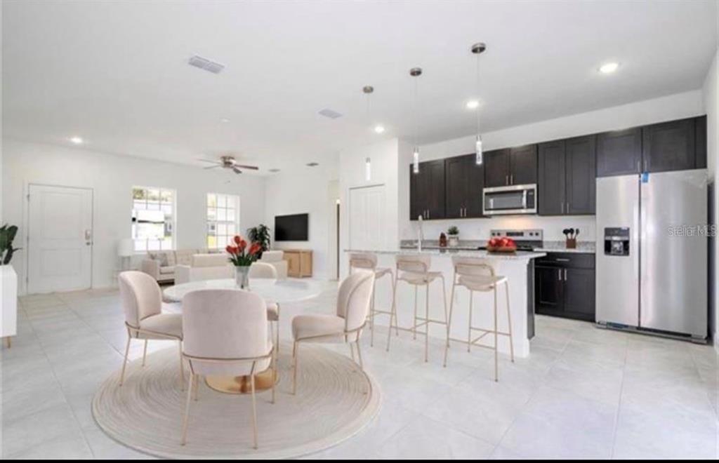 An open-concept kitchen with dark cabinetry and a dining area with a round table — 267 MARION OAKS GOLF ROAD, OCALA, FL