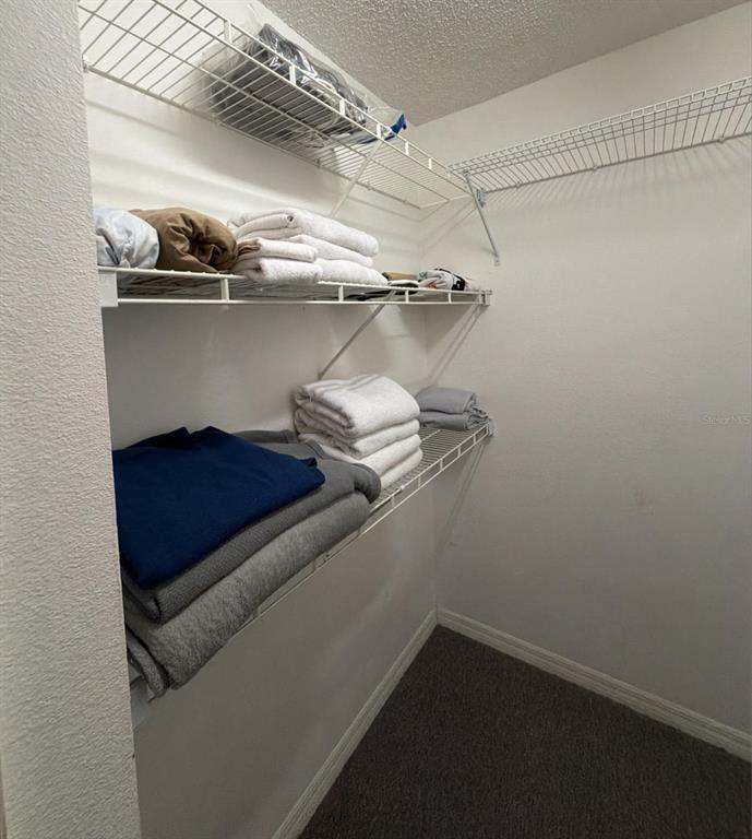 A walk-in closet features white wire shelving units holding folded towels and clothing — 2456 SWEETWATER CLUB CIRCLE UNIT 20, KISSIMMEE, FL