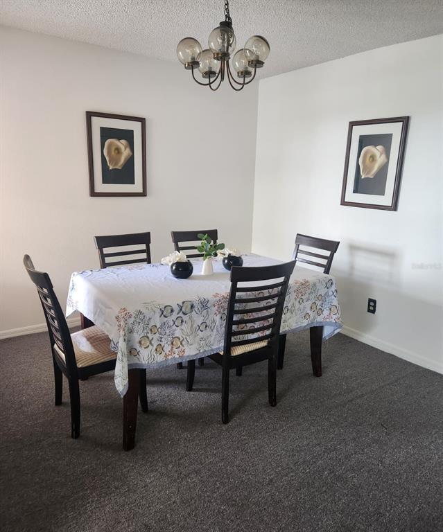 A dining room features a table with a patterned tablecloth, four chairs, and two framed pictures — 2456 SWEETWATER CLUB CIRCLE UNIT 20, KISSIMMEE, FL