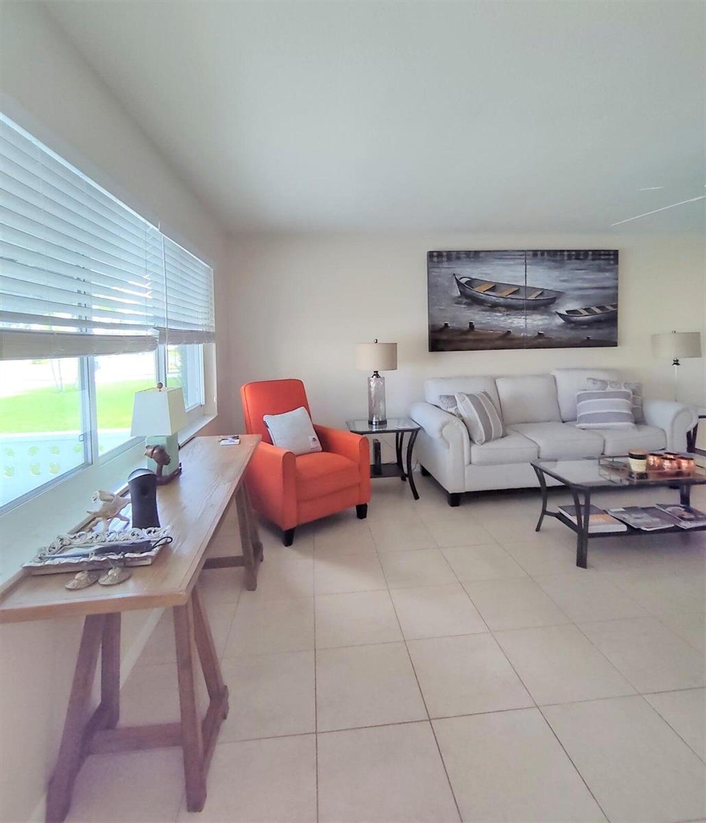 A living room features a white sofa, an orange armchair, and a wooden console table — 1826 SW Congress Boulevard, Boynton Beach FL 33426, BOYNTON BEACH, FL