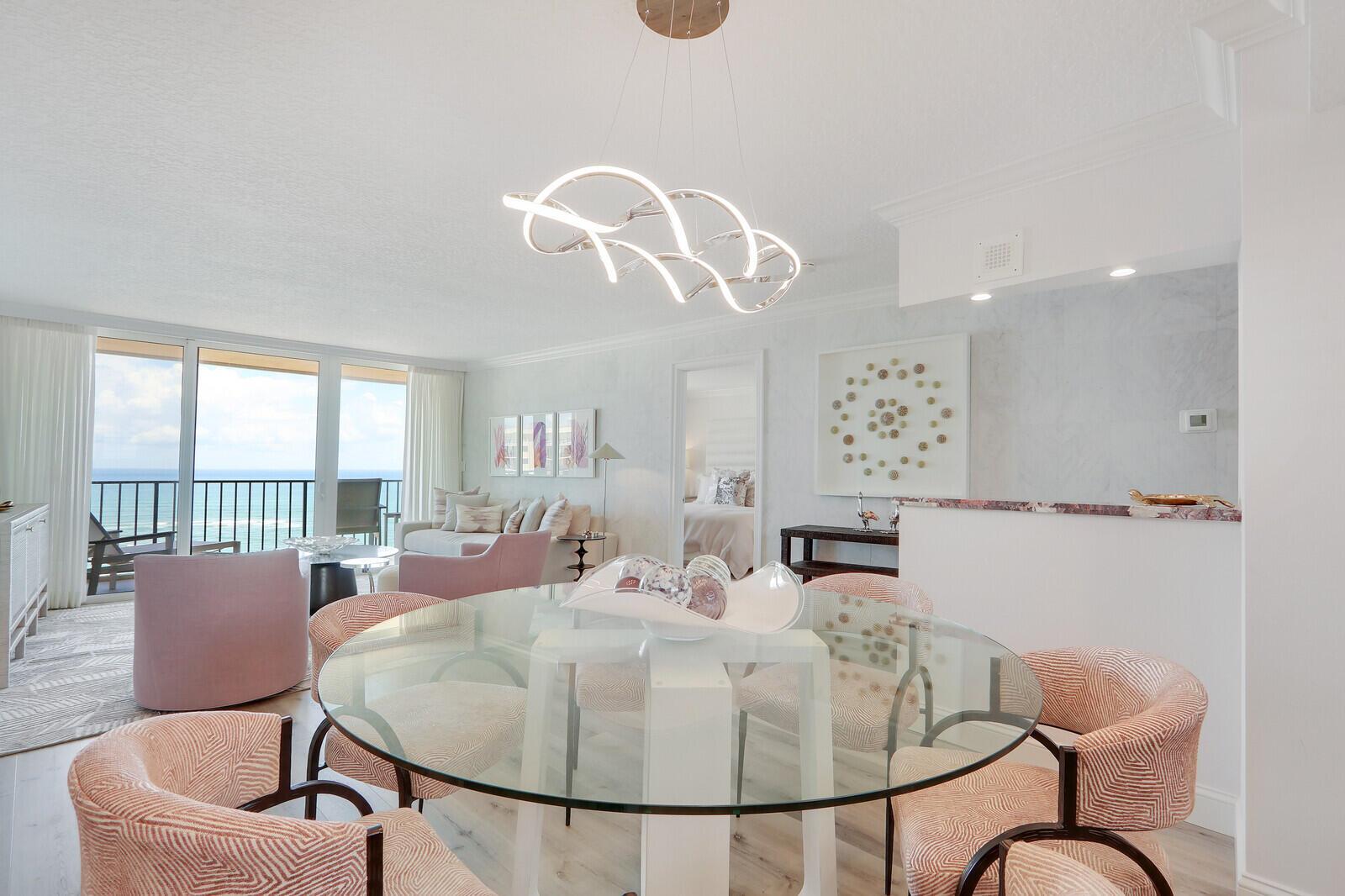 A dining area with a glass table and patterned chairs overlooks a balcony and ocean — 100 Ocean Trail Way, Jupiter FL 33477, JUPITER, FL