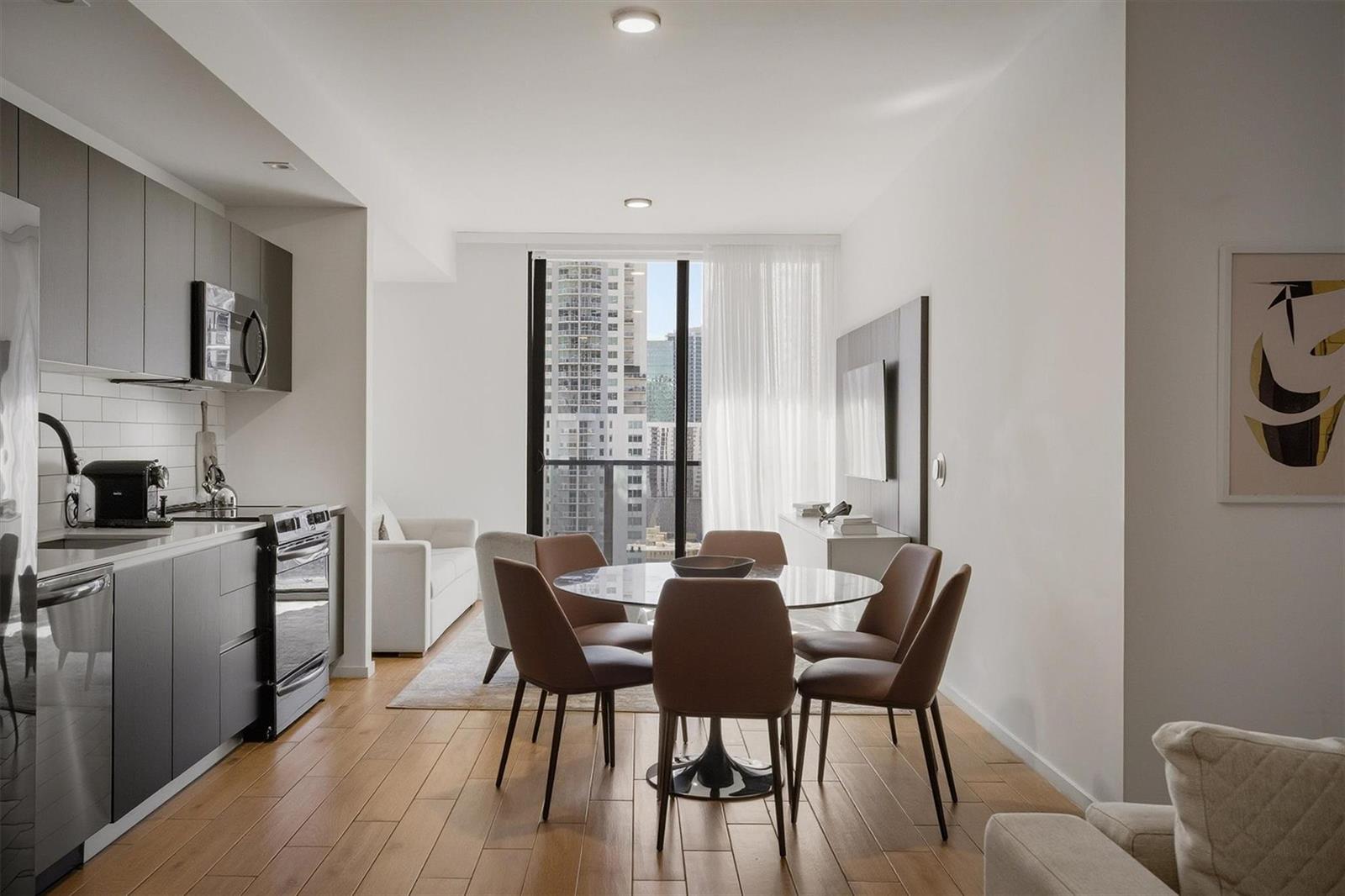 A modern apartment features an open kitchen, dining area, and floor-to-ceiling windows with city views — 398 NE 5th Street # 2017, Miami FL 33132, MIAMI, FL