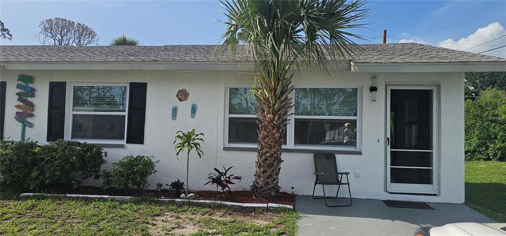 A white single-story house exterior features a palm tree, a front door, and two windows — 12048 HENLEY AVENUE UNIT B, PORT CHARLOTTE, FL