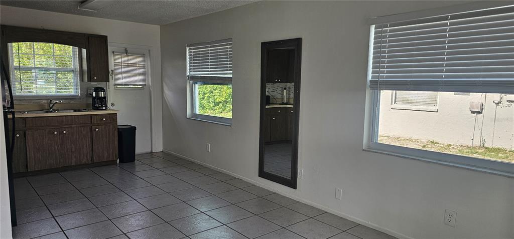 A kitchen and dining area with tile flooring, dark wood cabinets, and large windows — 12048 HENLEY AVENUE UNIT B, PORT CHARLOTTE, FL