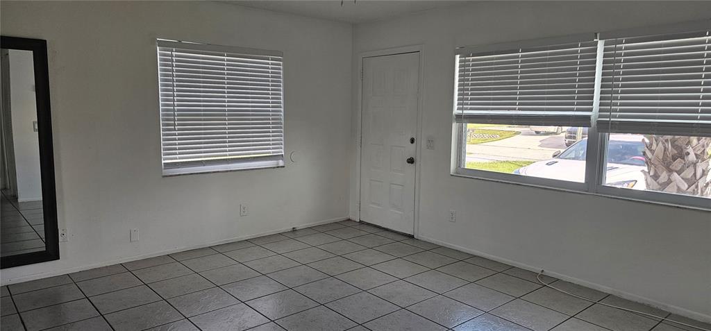 A room with white walls, tiled floors, a front door, and windows with blinds — 12048 HENLEY AVENUE UNIT B, PORT CHARLOTTE, FL