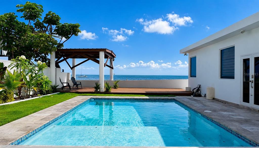 A swimming pool sits on a patio next to a white house overlooking the ocean — CARR 3 BO BAJOS VILLA PESQUERA, PATILLAS, PR