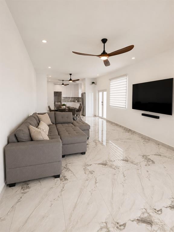 A modern open-concept living room features a gray sectional sofa, marble-look tile flooring, and ceiling fans — CARR 3 BO BAJOS VILLA PESQUERA, PATILLAS, PR