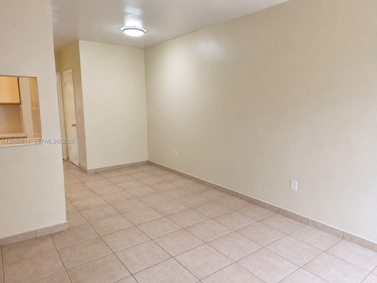 An empty room features beige walls, light-colored tile flooring, and a single ceiling light fixture — HOLLYWOOD, FL