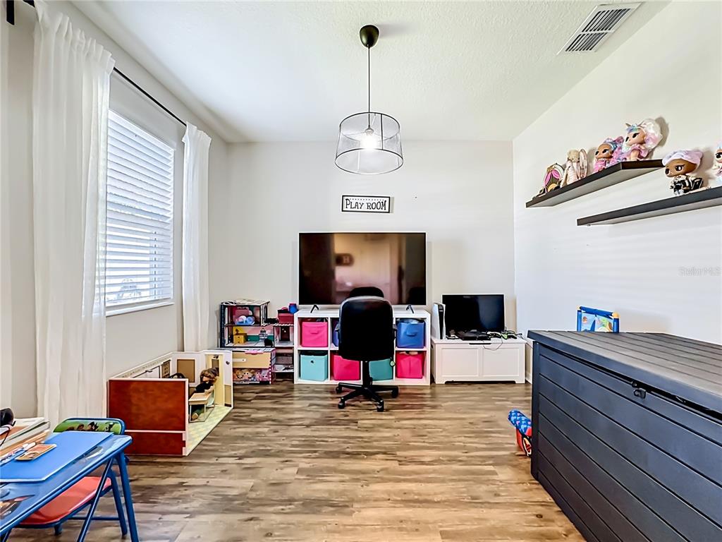 A playroom features wood-look flooring, a television on a storage unit, and wall-mounted shelves — 11205 BRIGHTON KNOLL LOOP, RIVERVIEW, FL
