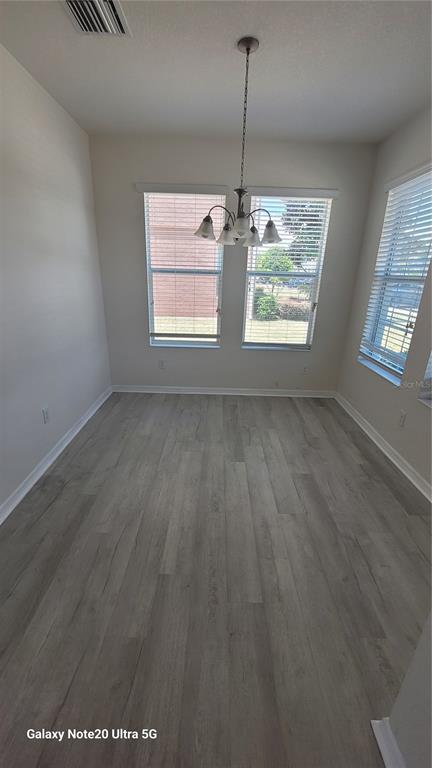 A dining area features light wood-look flooring, a chandelier, and windows with white blinds — 7005 TOWERING SPRUCE DRIVE, RIVERVIEW, FL
