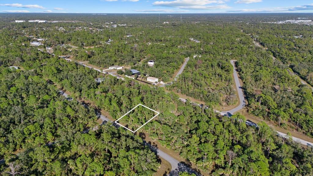 An aerial view shows a vacant, rectangular wooded lot outlined in white within a neighborhood — 1316 SHAKE STREET, PORT CHARLOTTE, FL