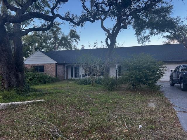 A single-story brick and siding house with a dark roof sits behind large oak trees — 610 VALLE VISTA DRIVE, BRANDON, FL
