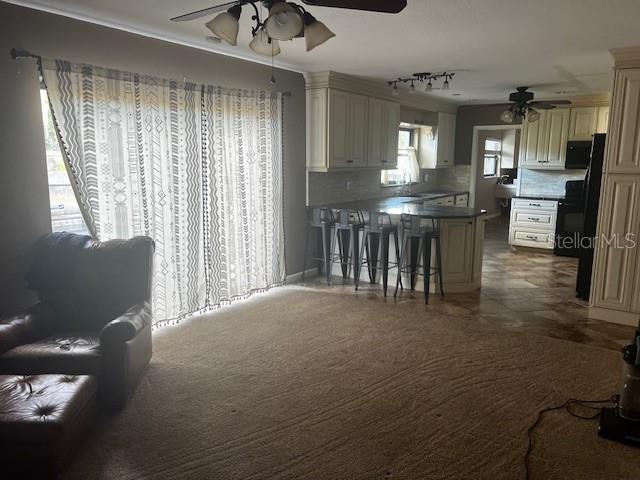 A living room with carpeted floors and a sliding glass door leads to a kitchen — 610 VALLE VISTA DRIVE, BRANDON, FL