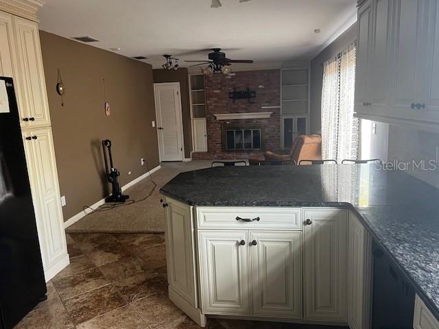 A kitchen with dark granite countertops and white cabinets overlooks a living room with carpet — 610 VALLE VISTA DRIVE, BRANDON, FL