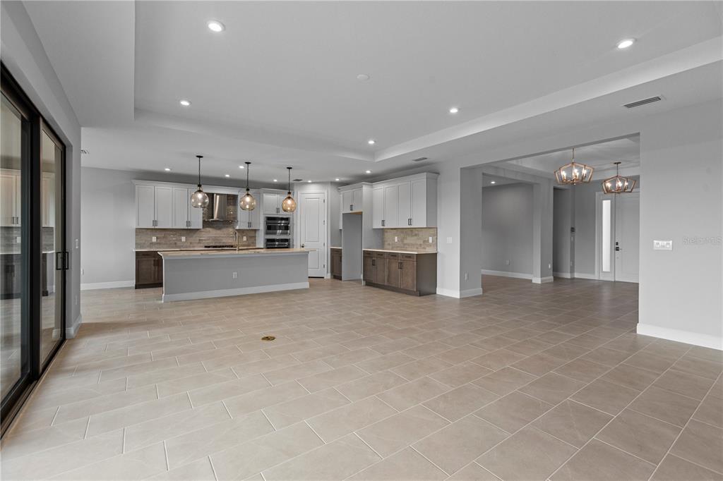 A spacious kitchen with a central island, white and dark cabinetry, and light tile flooring — 14443 COASTAL WOODLAND LANE, PARRISH, FL