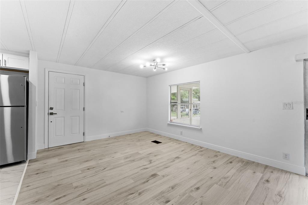 An open-concept living area with light wood-look flooring and a kitchen with stainless steel appliances — 130 FLORENCE BOULEVARD, DEBARY, FL