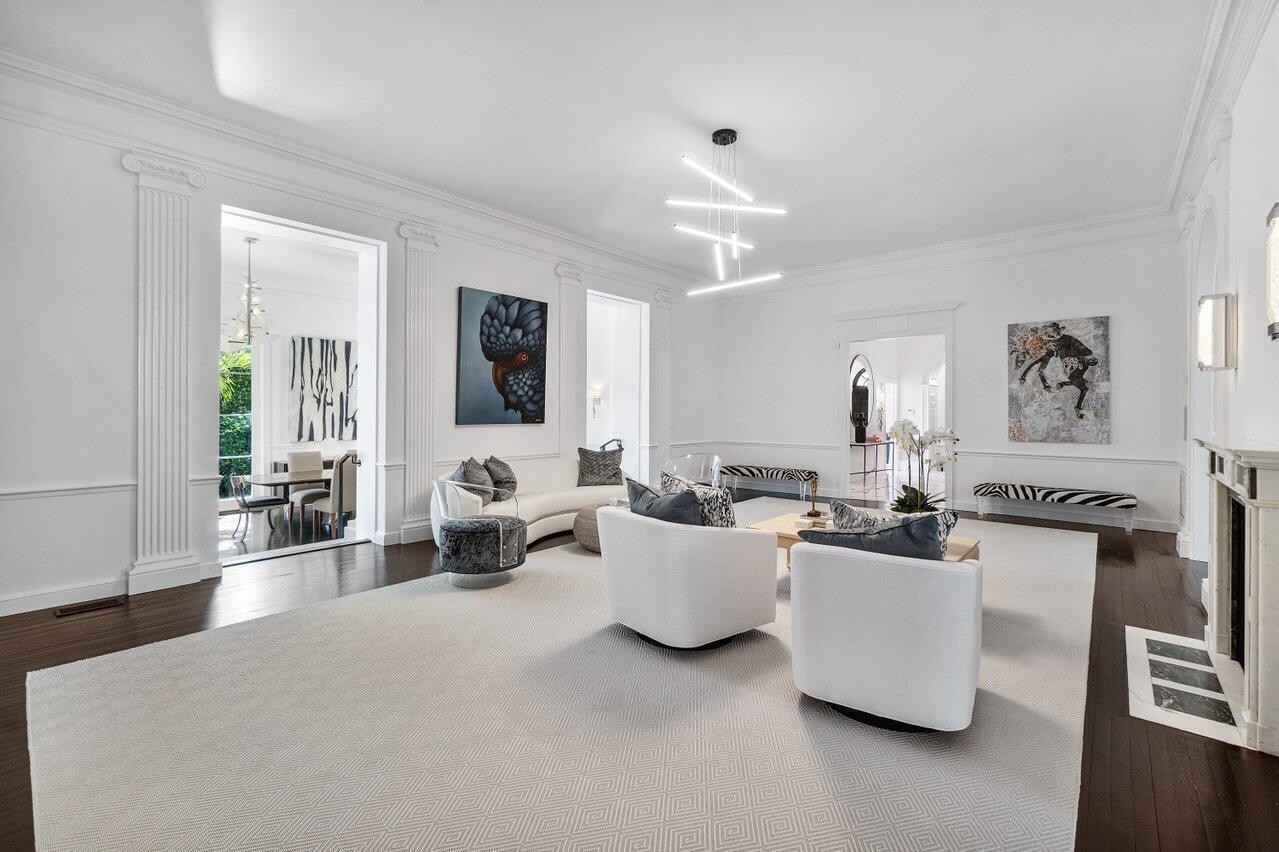A bright living room features white walls, dark hardwood floors, modern furniture, and contemporary artwork — 100 Regents Park Road, Palm Beach FL 33480, PALM BEACH, FL