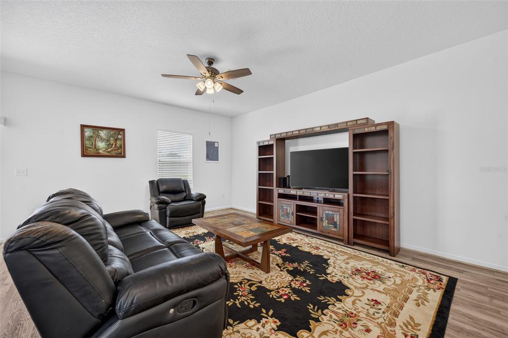 A living room features a black leather sofa, a matching recliner, and a large entertainment center — 16434 BLOOMING CHERRY DRIVE, GROVELAND, FL