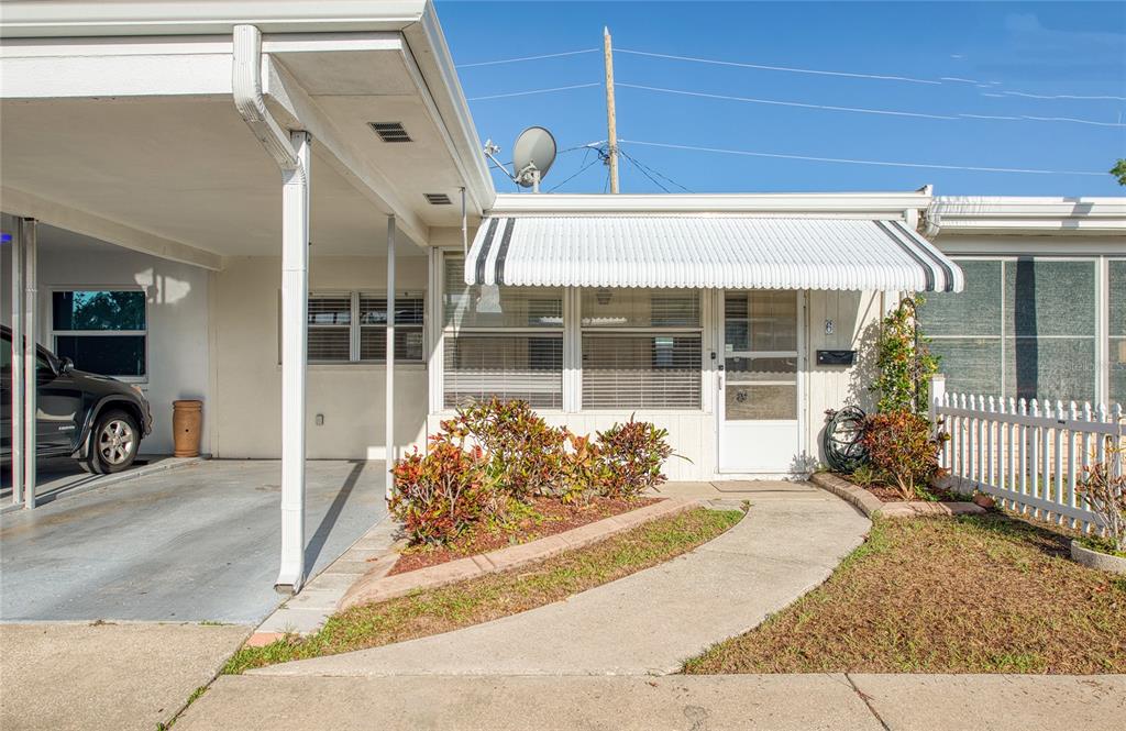 A single-story home exterior features a carport, a concrete walkway, and a white metal awning — 13940 ANONA HEIGHTS DRIVE UNIT 6, LARGO, FL