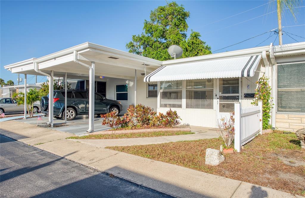 A single-story mobile home features a white carport, a small front garden, and an awning — 13940 ANONA HEIGHTS DRIVE UNIT 6, LARGO, FL