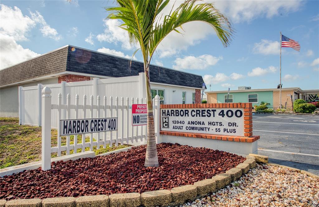 A sign for an adult community stands in front of a white fence and palm tree — 13940 ANONA HEIGHTS DRIVE UNIT 6, LARGO, FL