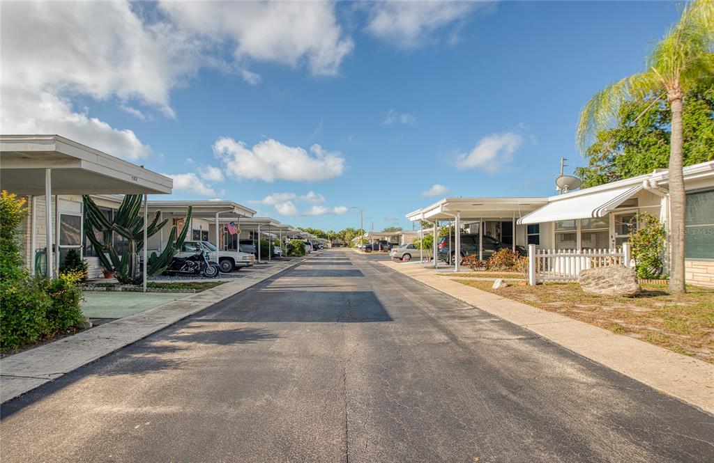 A paved street runs between two rows of single-story mobile homes with attached carports — 13940 ANONA HEIGHTS DRIVE UNIT 6, LARGO, FL