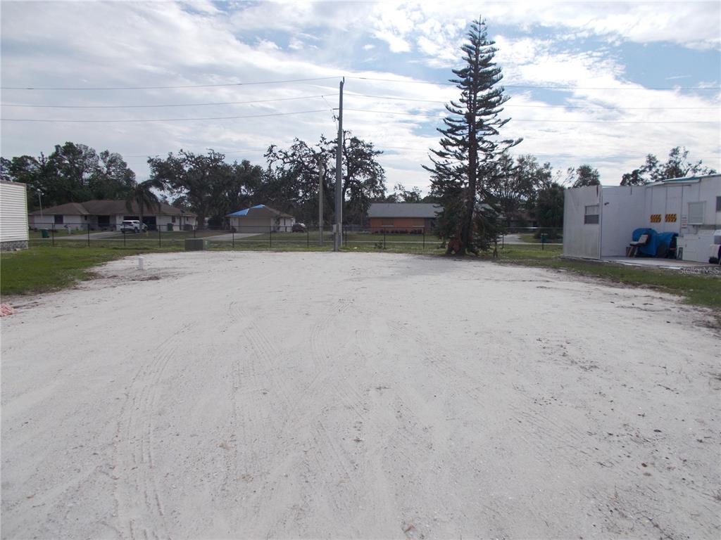 A vacant, sandy lot features a tall pine tree and a small white storage building — 5094 PALENA BOULEVARD, NORTH PORT, FL