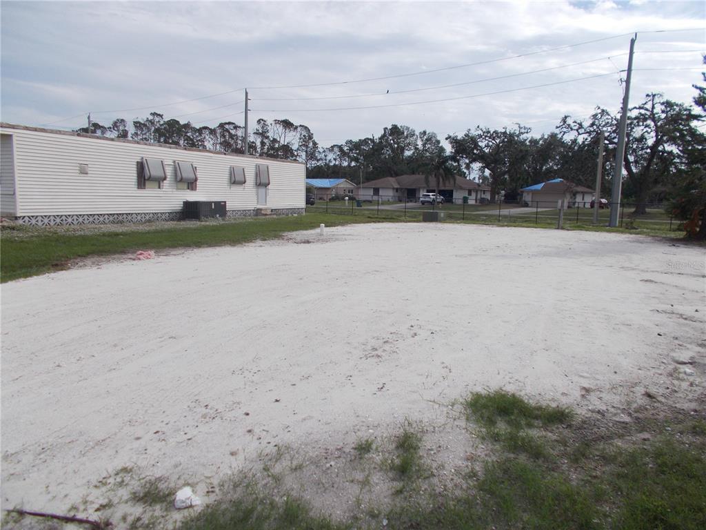 A large, sandy vacant lot sits next to a white mobile home — 5094 PALENA BOULEVARD, NORTH PORT, FL