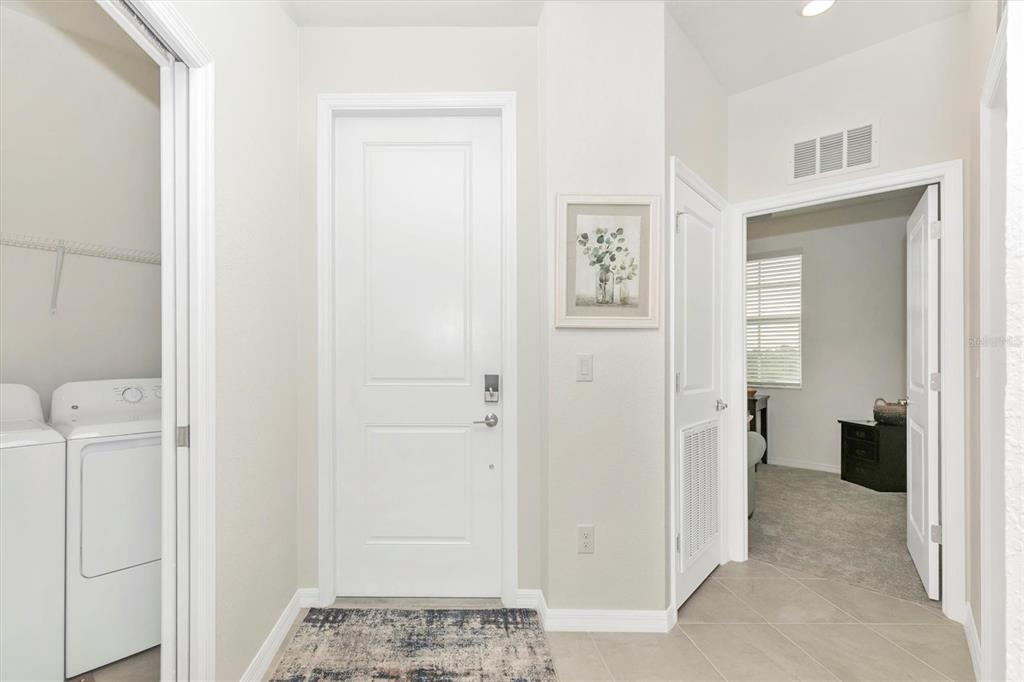 A hallway features a laundry closet, a central door, and an entrance to a carpeted room — 12280 WELLEN GOLF STREET UNIT 301, VENICE, FL