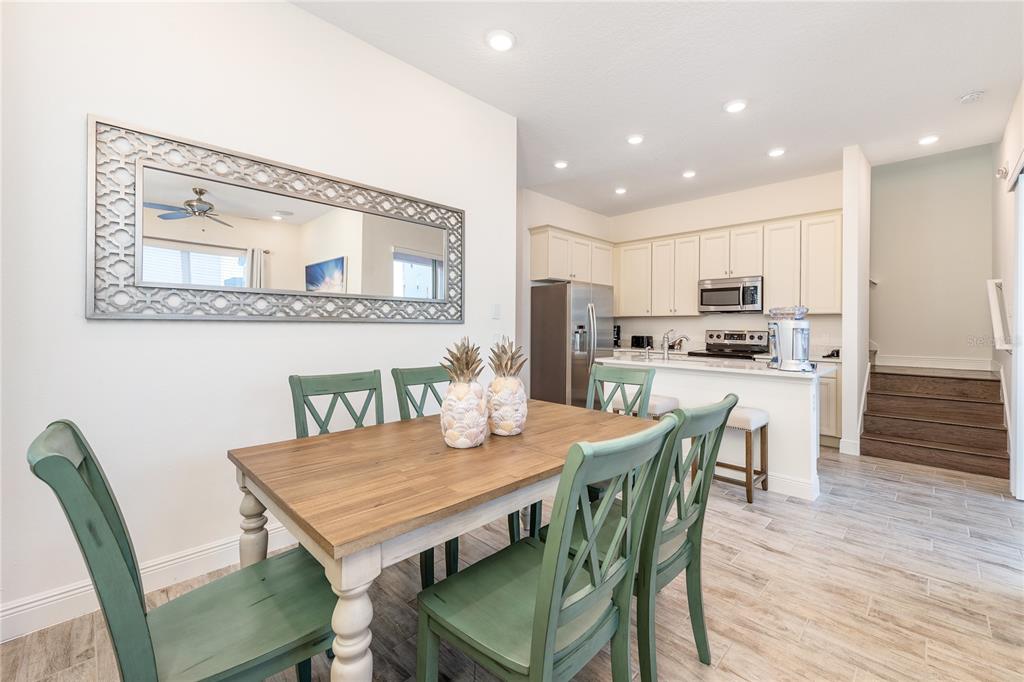 A dining area with a wooden table and green chairs sits before an open kitchen — 8075 KNEE DEEP ROAD, KISSIMMEE, FL