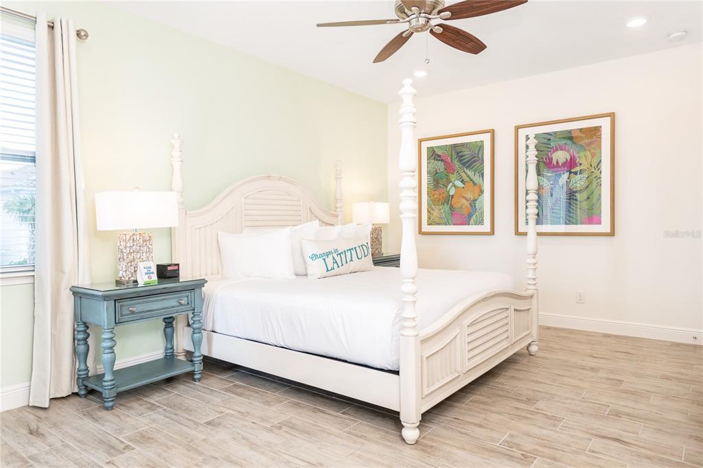 A bedroom features a white four-poster bed, a blue nightstand, and two framed botanical prints — 8075 KNEE DEEP ROAD, KISSIMMEE, FL
