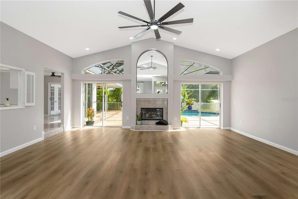 A spacious living room features light wood flooring, a fireplace, and sliding glass doors — 13640 MORNING COURT, HUDSON, FL