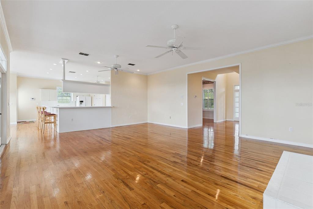 A spacious living area with hardwood floors, a kitchen island, and two ceiling fans — 25895 TILLY HAWK LANE, BROOKSVILLE, FL