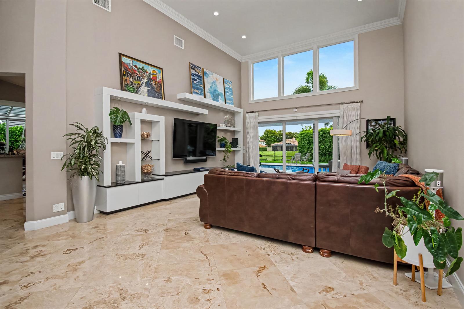 A living room with high ceilings, a large brown sectional, and a view of a pool — 2653 NW 46th Street, Boca Raton FL 33434, BOCA RATON, FL