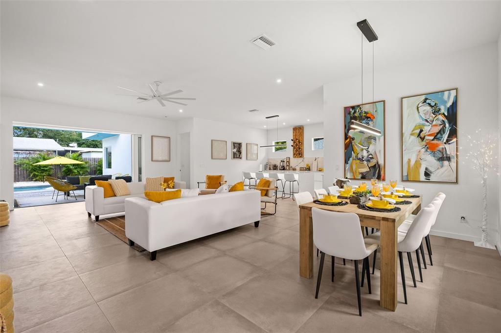 An open-concept living and dining area features white furniture, yellow accents, and large tile flooring — 2375 WALDEMERE STREET, SARASOTA, FL