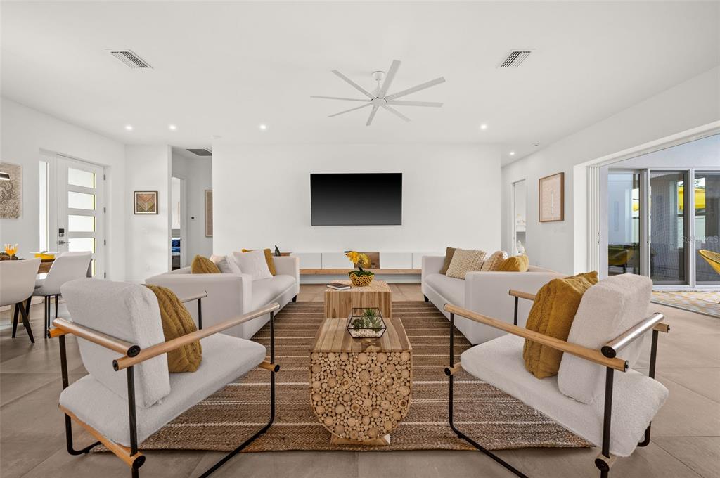 A bright living room features two white sofas, two armchairs, and a wood-textured coffee table — 2375 WALDEMERE STREET, SARASOTA, FL