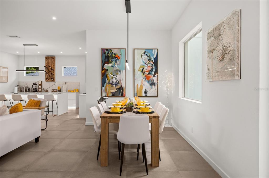 A dining area with a wooden table and white chairs sits adjacent to a modern kitchen — 2375 WALDEMERE STREET, SARASOTA, FL