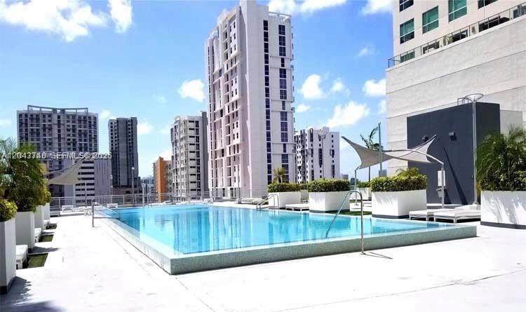 An outdoor swimming pool is surrounded by a concrete deck and modern high-rise buildings — 690 SW 1st Ct # 1019, Miami FL 33130, MIAMI, FL