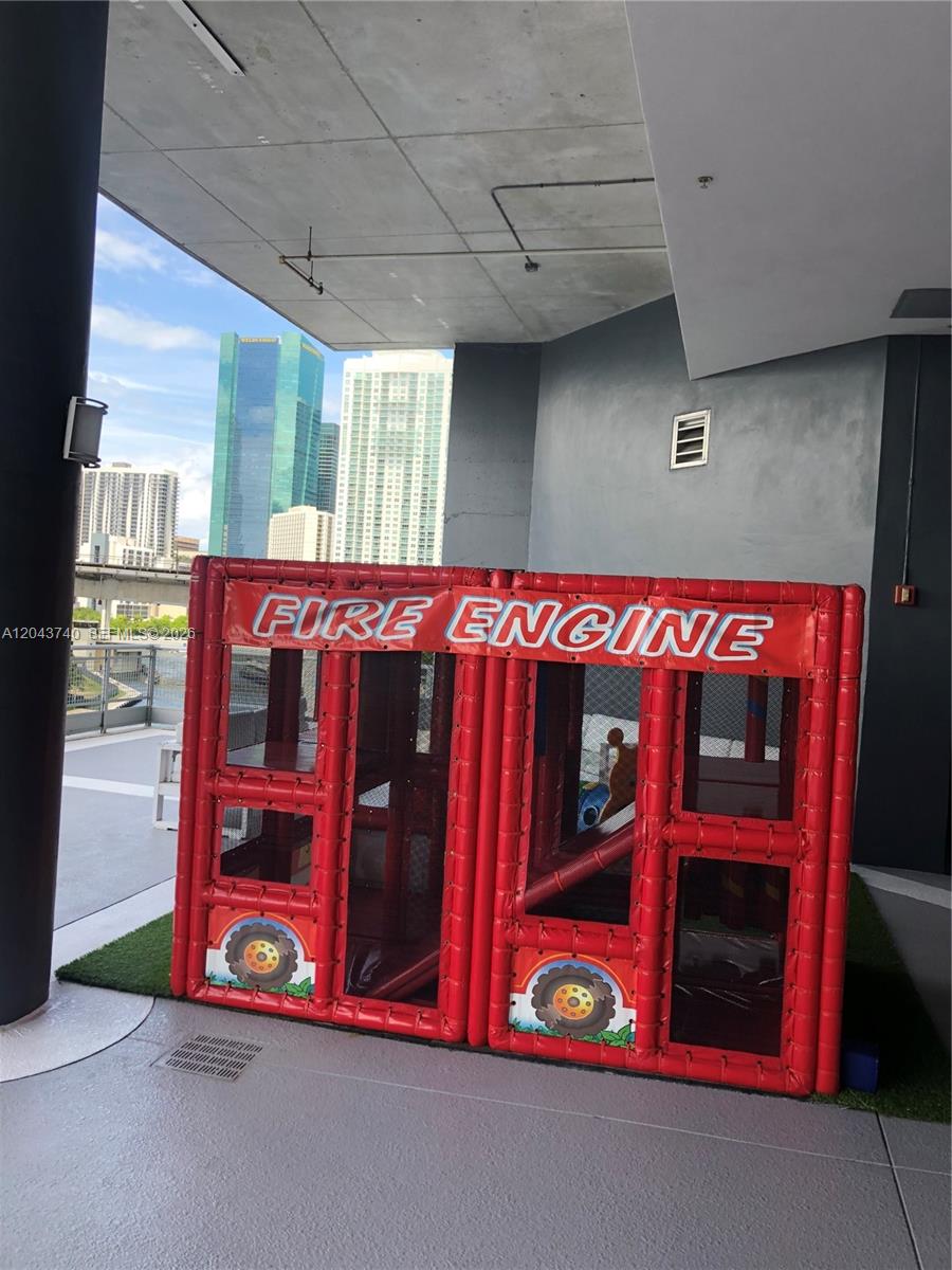 A red inflatable fire engine play structure sits on a balcony overlooking city buildings — 690 SW 1st Ct # 1019, Miami FL 33130, MIAMI, FL