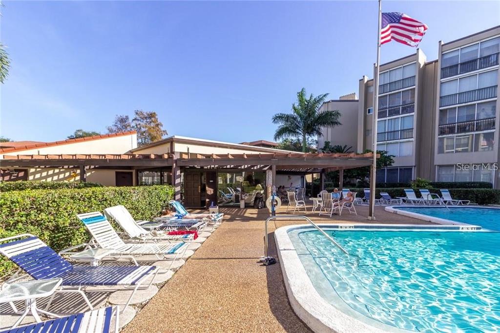 A swimming pool with lounge chairs sits in front of a multi-story apartment building — 1245 S MARTIN LUTHER KING JR AVENUE UNIT 104, CLEARWATER, FL
