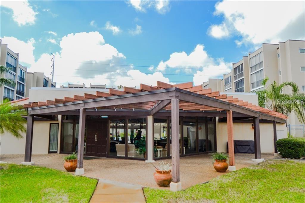 A wooden pergola covers a patio area in front of a building with glass walls — 1245 S MARTIN LUTHER KING JR AVENUE UNIT 104, CLEARWATER, FL